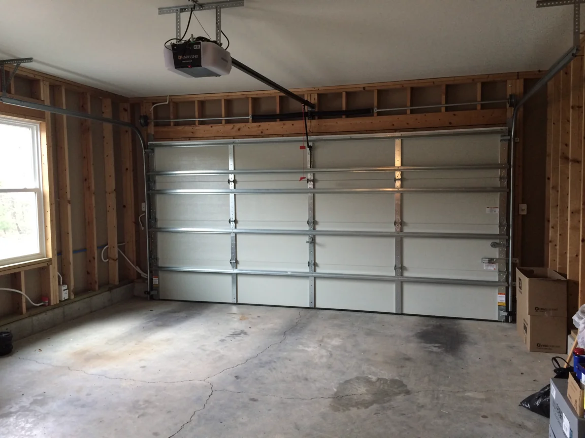 The garage door is closed in a newly framed garage with an opener.